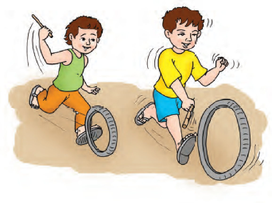 A boy is moving a tyre on a road with a stick and behind him is another boy moving a smaller tyre with a stick.