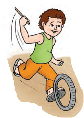 एक लड़का सड़क पर एक छोटे से टायर को लाठी से घुमा रहा है 