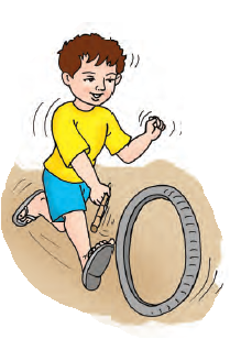 एक लड़का सड़क पर एक बड़े टायर को लाठी से घुमा रहा है 