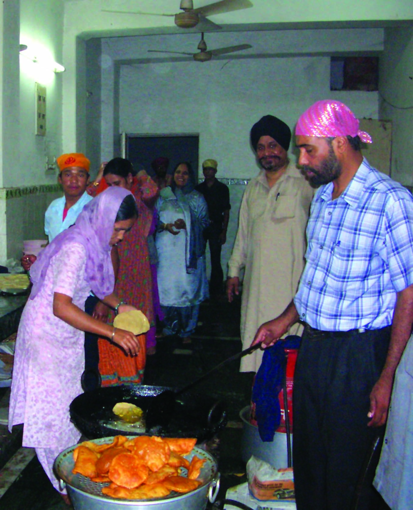 People cooking in the kitchen of a Gurudwara. 
