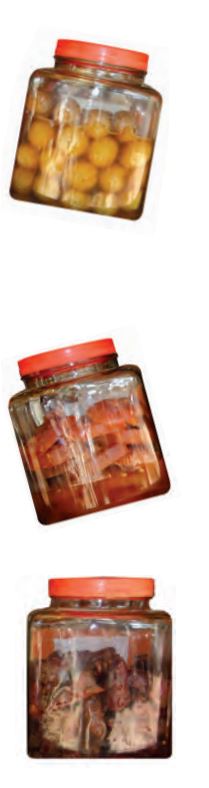 Three glass jars with some pickles, chutney, aam papad in it.