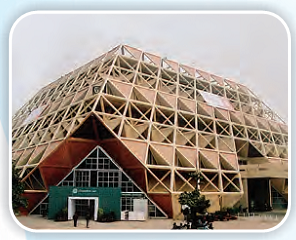 A building with a triangular shaped structure over the entry gate and there are a lot of small triangles on all the walls o the building.