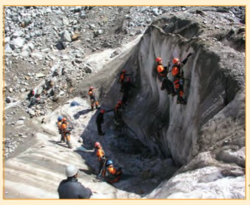 कुछ पुरुष रस्सियों का उपयोग करके पहाड़ पर चढ़ रहे  हैं।