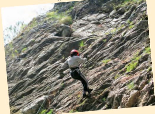 रस्सियों के सहारे चट्टान पर चढ़ती महिला।