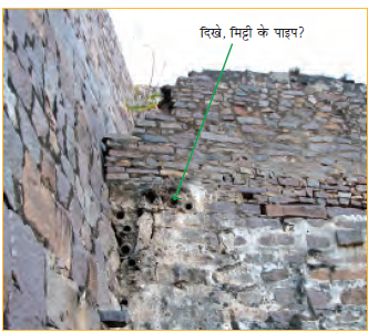 चट्टानों के बीच रखे बेलनाकार आकार के पानी के पाइप। 