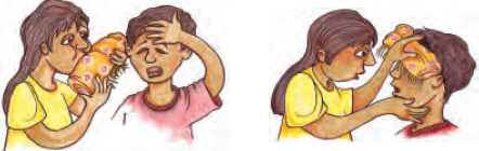 एक लड़की तीन-चार बार मुड़े हुए कपड़े के टुकड़े पर जोर से फूंक मार रही है और उसके पास खड़े लड़के के माथे पर रख रही है।