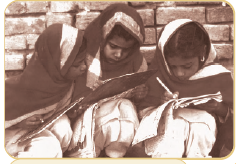 सिर पर दुपट्टा ओढ़े तीन छोटी बच्चियां पढ़ रही हैं। 