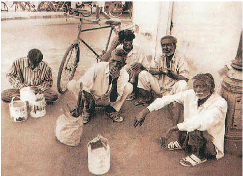 कुछ मजदूर अपने औजारों के साथ नीचे  बैठे हैं। 