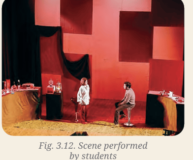 A stage with red geometric panels and actors