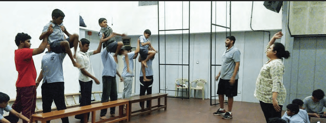 Students practicing physical theatre under teacher supervision