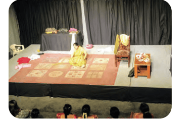 A solo actor performing on a stage set with traditional floor patterns