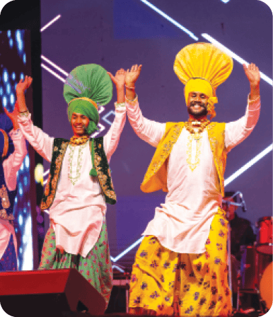 Four men wearing turbans and yellow hats are dancing on stage.  AI generated content