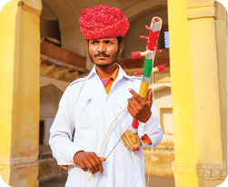 A man wearing a red turban and white outfit is holding a large toothbrush.  AI generated content